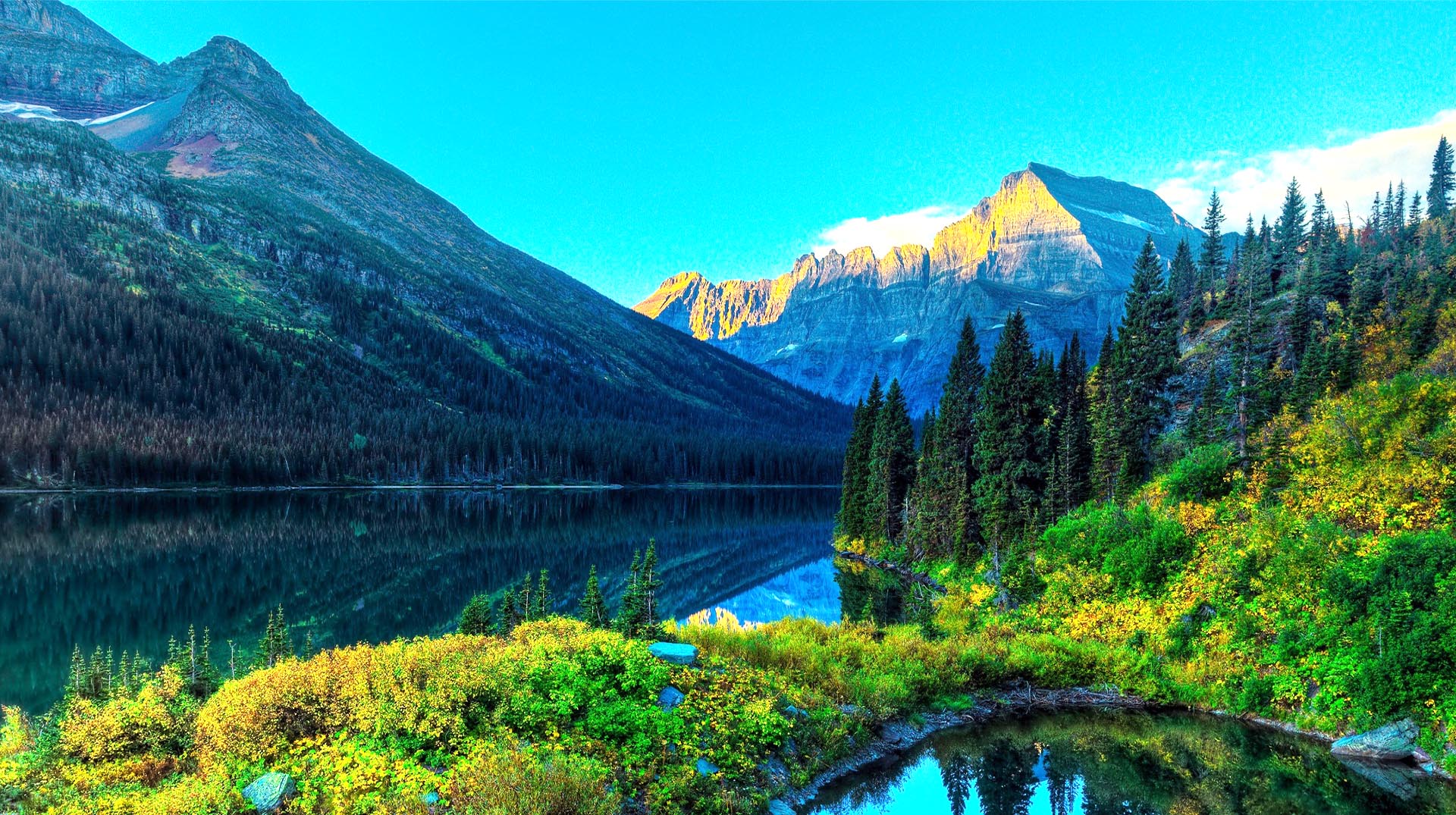 A lake with mountains in the background and trees.