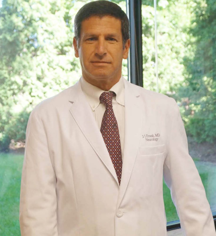 A man in white lab coat and tie standing next to window.