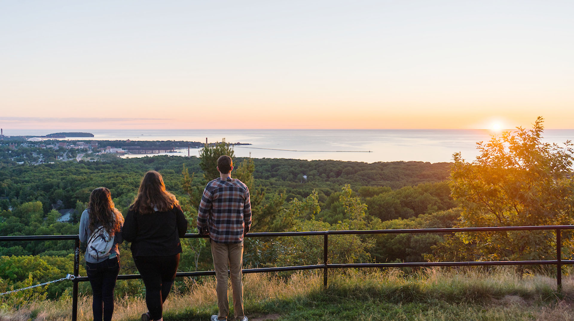 Two people standing on a hill overlooking the ocean.