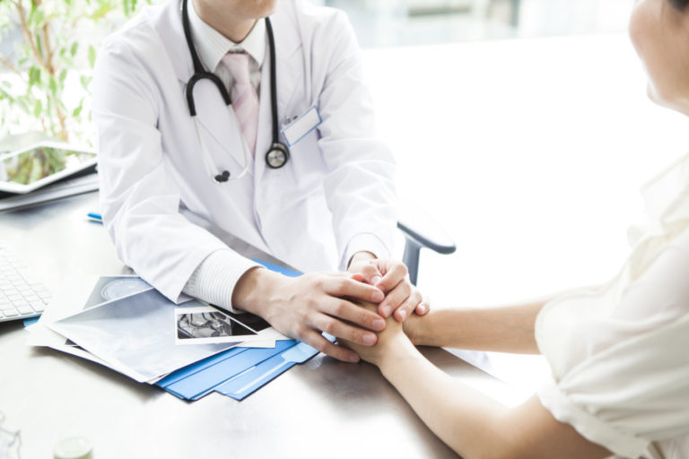 A doctor is holding the hands of a patient.